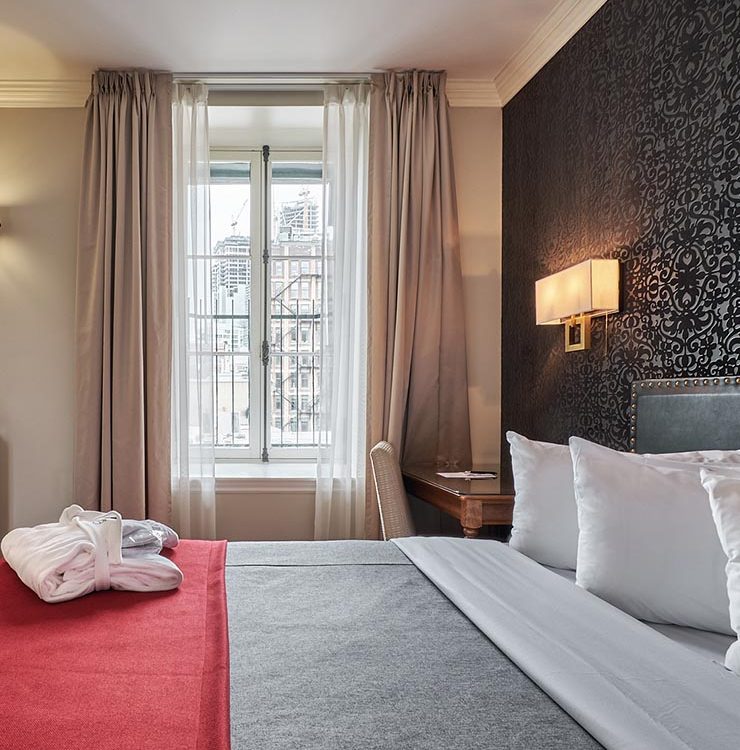 King bed with tall window and view onto Old Montreal at Hotel Bonaparte