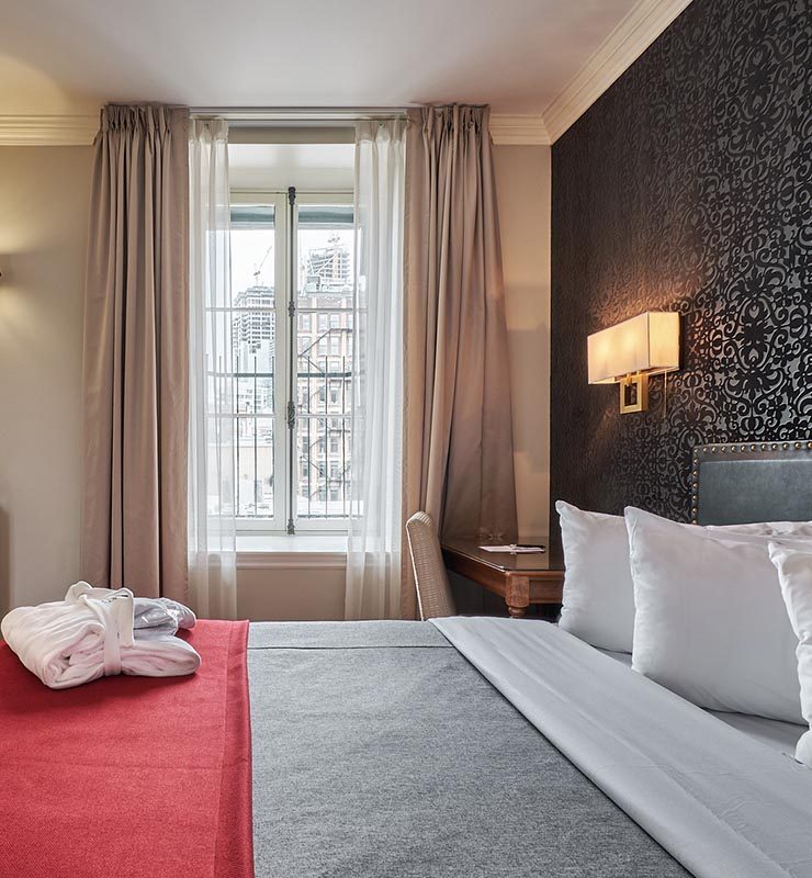King bed with tall window and view onto Old Montreal at Hotel Bonaparte