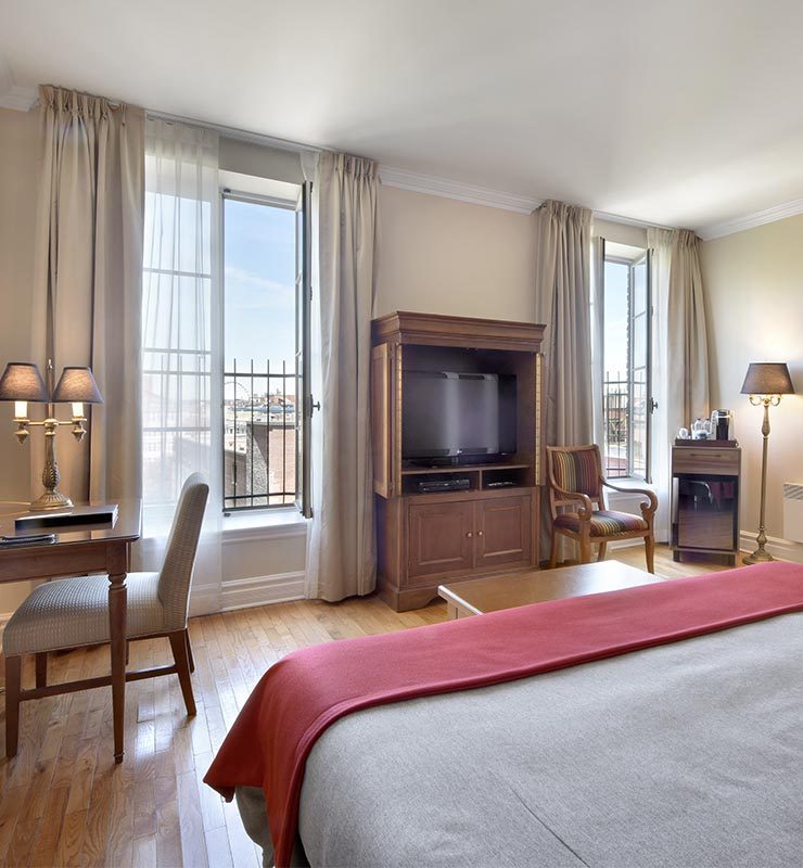 King Superior room, king bed with view of Old Montreal through tall windows.