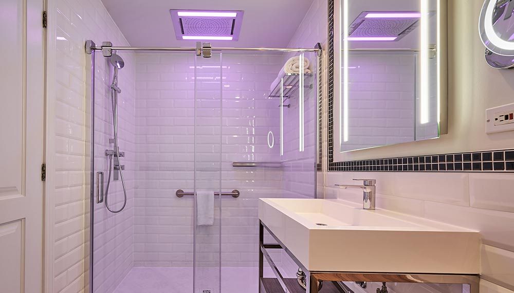 Modern bathroom with faint purple lights and white tiles.