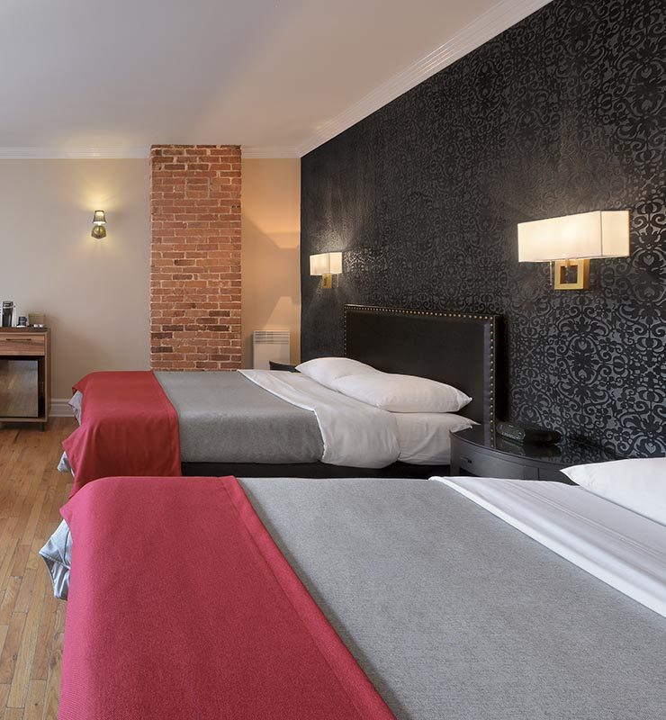 Two queen beds with hardwood floor and black wallpaper