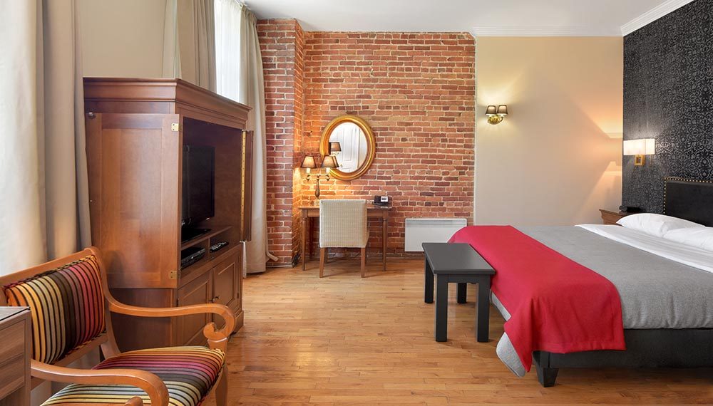 King bed with desk and hardwood floors, brick wall in Old Montreal's Hotel Bonaparte